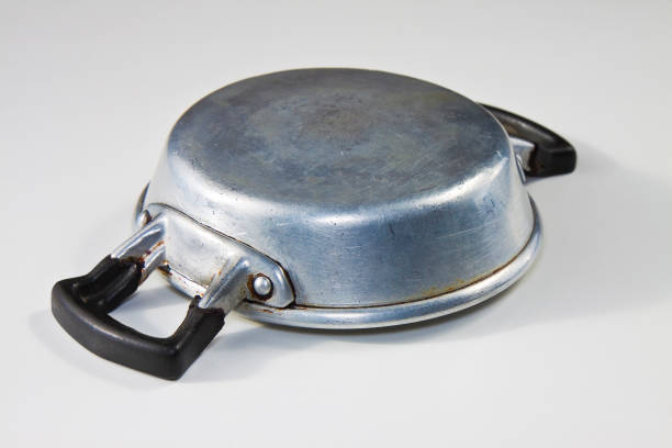 Old upset aluminum pan seen from above on white background