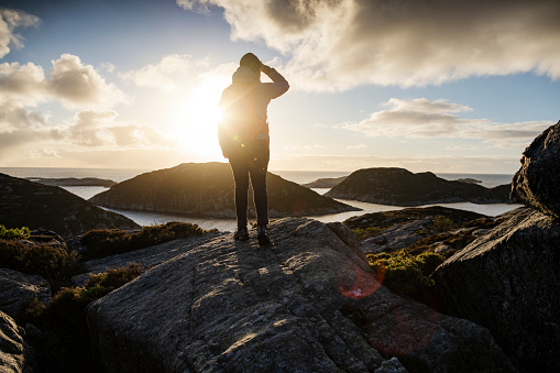 Woman outdoor adventures: hiking in Norway, on the mountain by a fjord