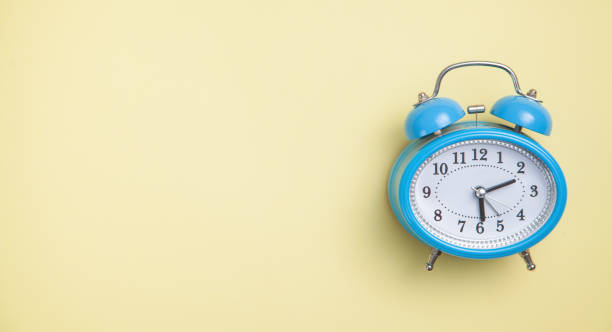 istock Alarm clock on yellow background. Top view 1204371243