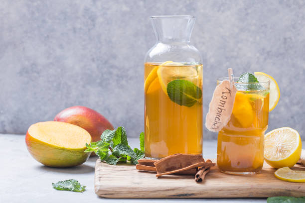 Kombucha or cider fermented drink. Cold tea beverage with beneficial bacteria, cinnamon, lemon on concrete  background side view with copyspace. For healthy nutrition. stock photo