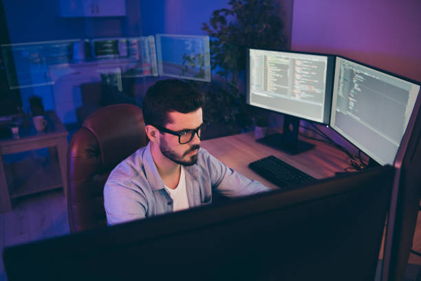 istock Photo of it specialist guy sitting comfy chair looking many monitors testing website algorithms serious content development expert dark night office indoors 1204373314