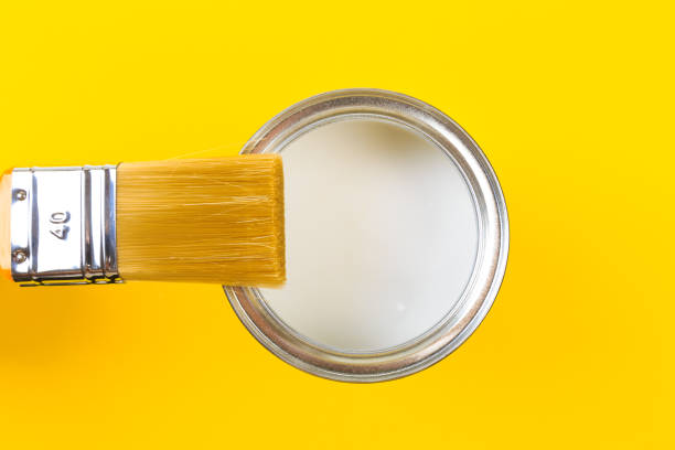 istock White Paint Can with Brush Top View On Yellow Background. 1204375264