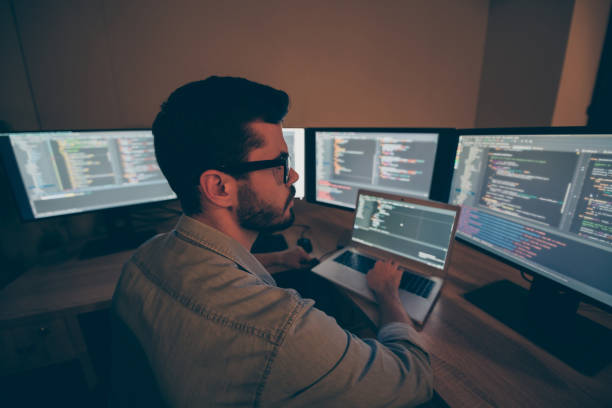 istock Photo of C specialist serious thinking on improving the code of securing software to prevent hackers from cyber attacking the servers of corporation he creates software for texting before laptop 1204375407