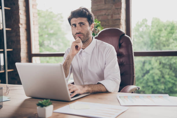 istock What answer.... Portrait of doubtful thoughtful  business, man using his laptop communicate with enterprise partners investors want find solution decision to get aim sit table in loft 1204375427