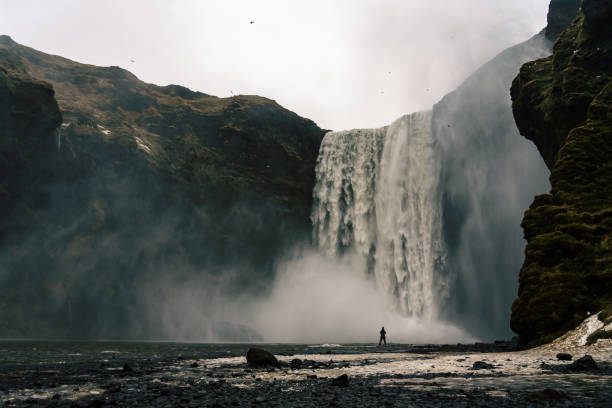 Photo of woman standig bevore the majestic skogafoss waterfall in Iceland winter time