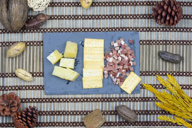 sliced ham and sheep cheese on black slate plate on wooden table