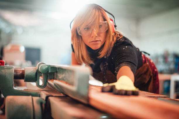 istock Craftswoman using a saw guide to cut a wooden plank on a work bench 1204380672