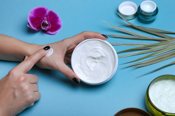 istock Woman's hands holding jar with cream over blue table 1204382816