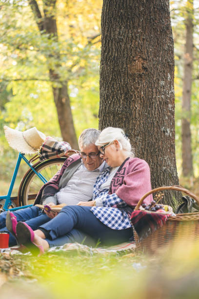 istock Lovely senior couple resting at park, reading a book 1204384030