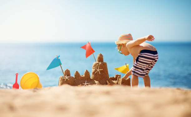 istock boy building a sandcastle at the beach in summer 1204387460
