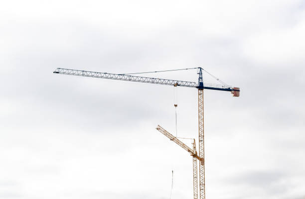 istock Blue and yellow cranes with the cloudy sky in the background. Construction concept 1204388322