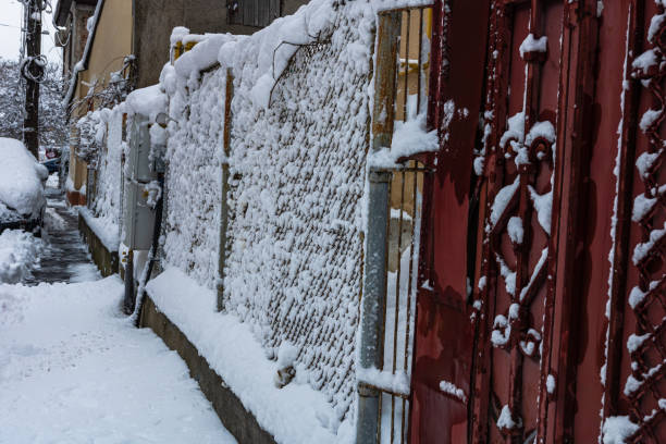 Wire fence metallic net with snow. Metal net in winter covered with snow.