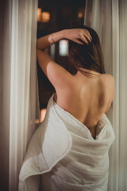 istock A woman stands by a window wrapped in linen 1204389166