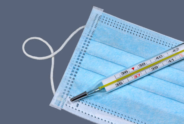 istock Thermometer on the medical face mask close up 1204390345