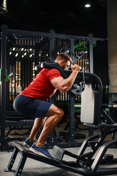 istock Athletic man doing legs exercise on squat machine at the gym 1204390441