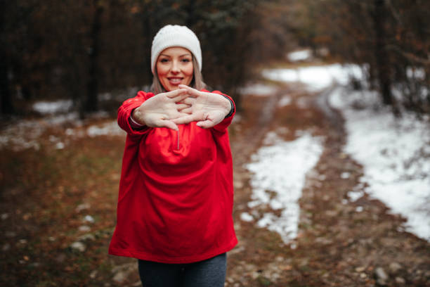 Overjoyed blonde woman in blue raincoat enjoying silence natural green environment woods in the forest. Happy emotion open arms outdoors in rainy weather. Unity with nature physical mental wellbeing