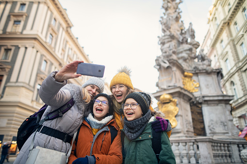 Mother and kids sightseeing Vienna. The family is taking selfies near Column of Pest monument (Wiener Pestsäule).