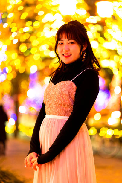 istock Young woman standing against illuminations background 1204392371