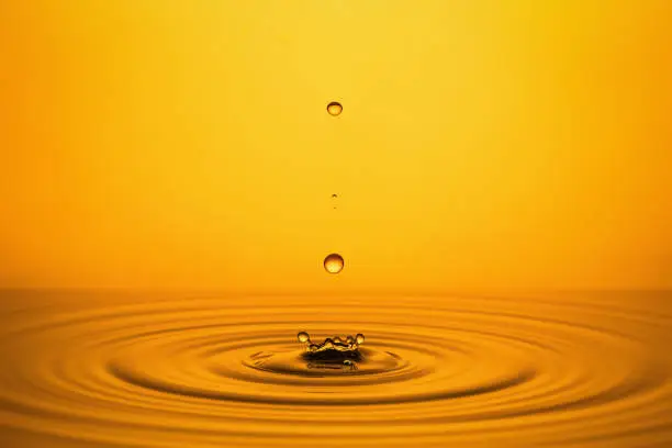 Photo of Golden Oil Drops on Yellow Background.