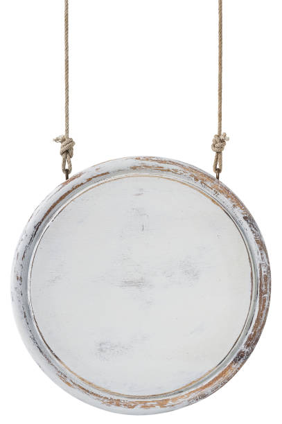 istock Old weathered worn white circular wooden board sign panel, hanging by old rope, isolated on white, clipping path included. 1204394336