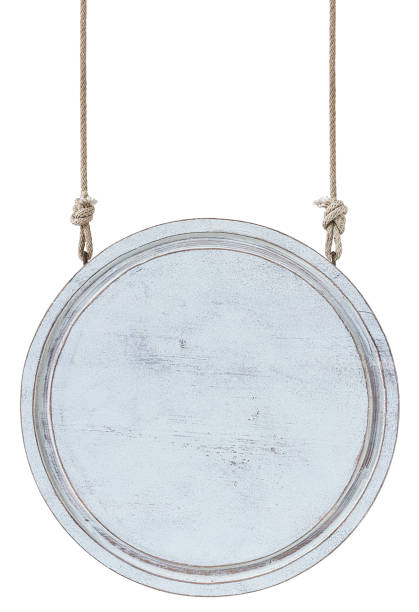 istock Old weathered worn white circular wooden board sign panel, hanging by old rope, isolated on white, clipping path included. 1204394343