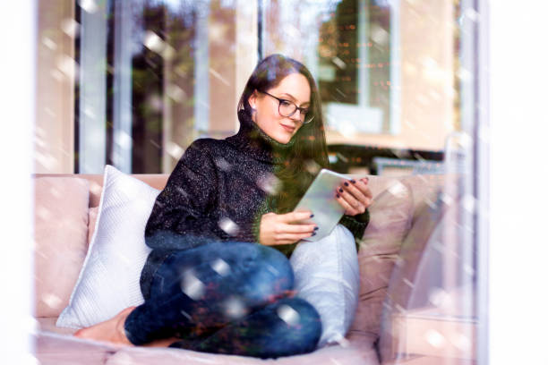 istock Relaxed young woman using her touchpad while sitting on couch at home 1204394456