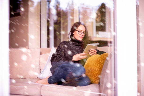 Relaxed young woman using her touchpad while sitting on couch at home