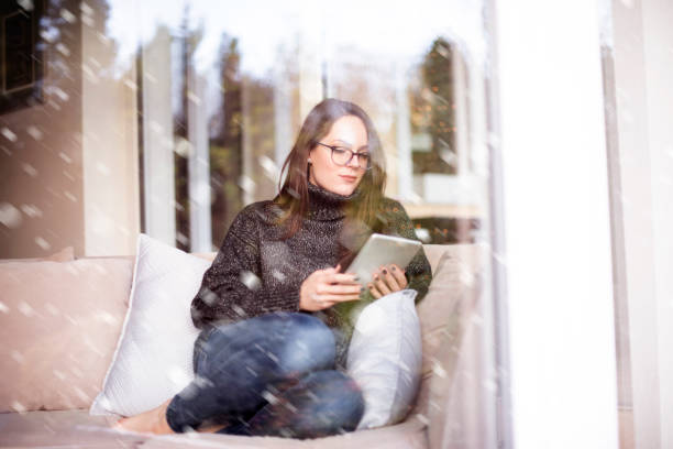 istock Relaxed young woman using her touchpad while sitting on couch at home 1204394460