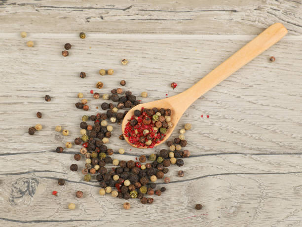istock Mixed pepper and spoons on wooden table background 1204394628