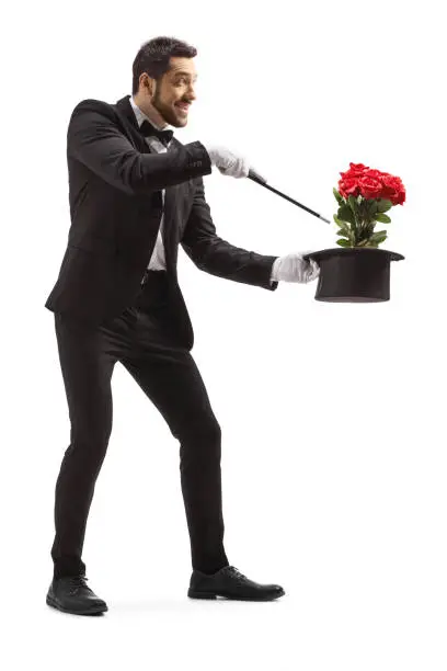 Full length shot of a magician performing a trick with hat and red roses isolated on white background