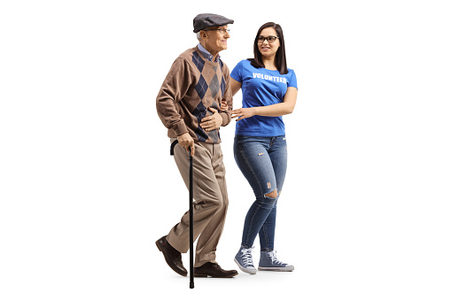 Full length shot of a young female volunteer helping an elderly man with a walking cane isolated on a white background