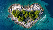 Aerial view of the heart shaped island . Blue ocean sea with wave and small forest and rocky coastline.