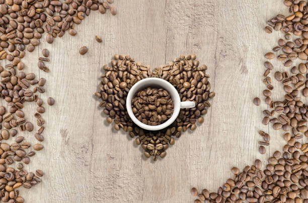 istock Love coffee heart center white cup. Split spilt beans wooden table top down view. 1204395807