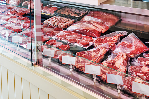 Variety of raw fresh veal meat in the refrigerated display of a butcher shop