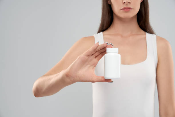 istock Female holding white container of pills. 1204396745