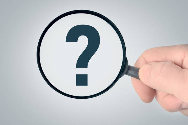 istock Magnifier in a man’s hand, question mark on a blue background. 1204399232