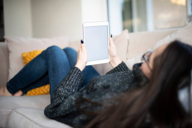 istock Woman with digital tablet in her hand relaxing on sofa at home 1204399921