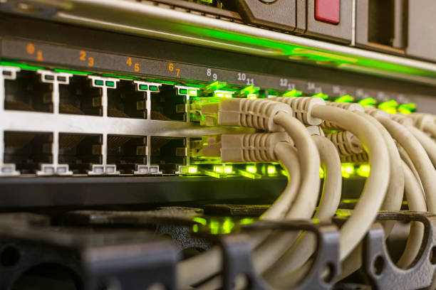 灰色のケーブルは、緑色の表示が付いているネットワークインターフェイスに含まれています。最新の機器は、データセンターのサーバールームにあります。多くのインターネットワイヤが� - cable network server network connection plug green ストックフォトと画像
