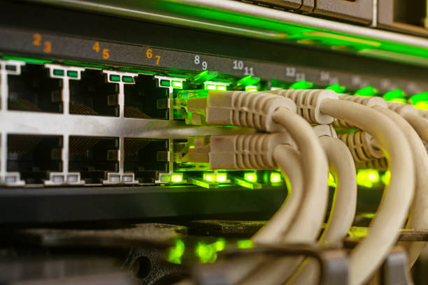 通信機器は、データセンターのサーバールームにあります。多くのインターネットワイヤがメインルータに接続されています。灰色のケーブルは、緑色の表示が付いているネットワークイン� - cable network server network connection plug green ストックフォトと画像