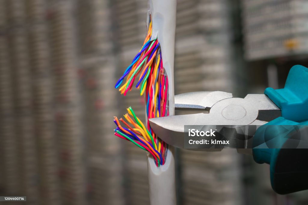 Cutting a multicore cable with a cushion. Network internet cable is torn with a sharp tool. The concept of vandal damage to the trunk. Cutting Stock Photo