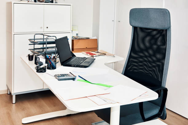 istock Office workplace with chair, laptop computer and a messy table with papers on it 1204400745