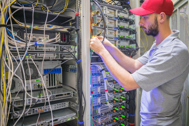 ネットワーク エンジニアは、サーバー ルーム ラックの電源ケーブルを切り替えます。システム管理者はデータセンターで作業します。コンピュータ機器を扱う技術者の肖像 - messy network server cable computer ストックフォトと画像