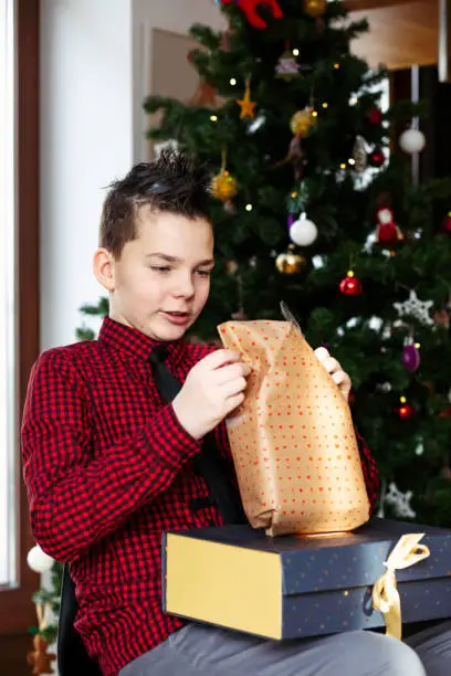 January 12, 2020 - Warsaw, Poland: teenage handsome boy unwraps Christmas gift