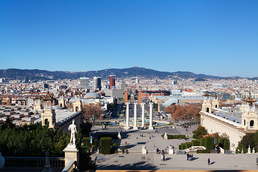 View from MNAC over Plaça de les Cascades to Placa de Espanya in Barcelona at winter season. High angled view with street Avinguda de la Reina Maria Cristina in center. People are walking up and down from and to museum and to square with columns.
