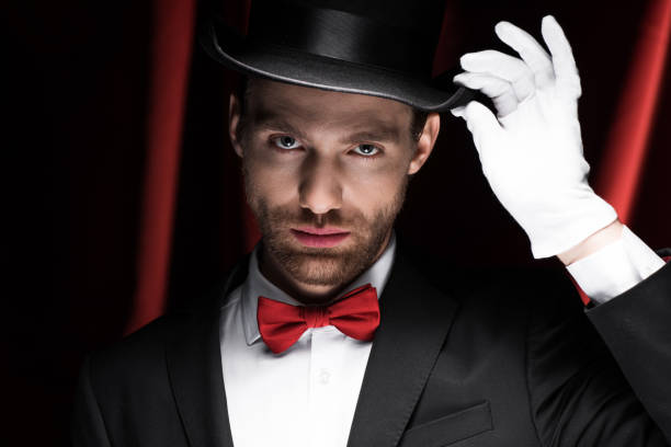 istock handsome gentleman in suit and hat in circus with red curtains 1204403008