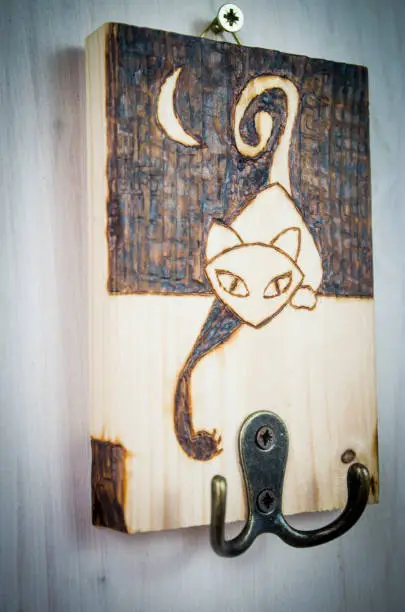 Photo of the ancient art of pyrography, wood and fire, curious cat who tries to take keys and objects