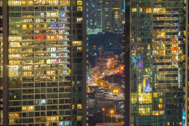 istock Pattern of office buildings windows illuminated at night. Lighting with Glass architecture facade design with reflection in urban city, Downtown Singapore City in financial district. 1204405062