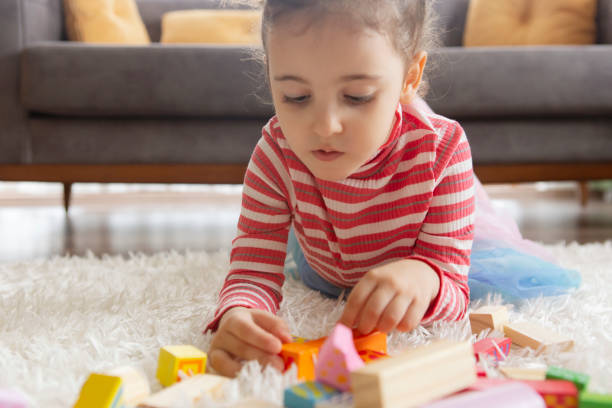 istock Little girl playing with toy blocks 1204405103