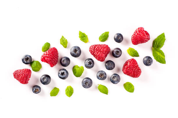 istock Fresh raspberries and blueberries with mint leaves on a white background. 1204405218