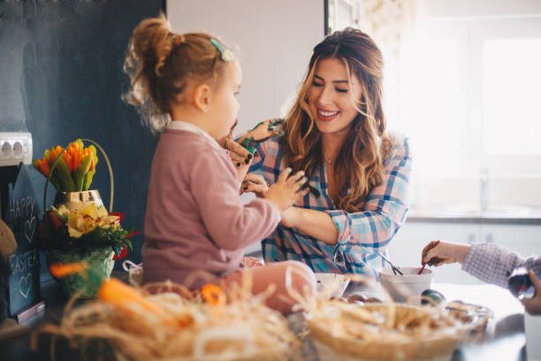 istock A mother with her two daughters having fun while painting eggs for Easter. The hands of her daughters are smeared with various paint. 1204406253
